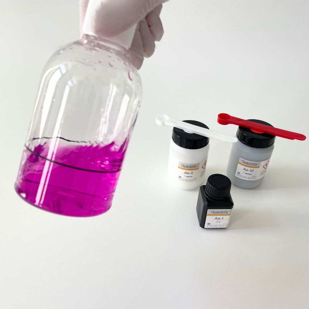 Reagenzglas mit pinken Flüssigkeit und einigen Chemikalienbehälter aus dem Quantofix-Koffer