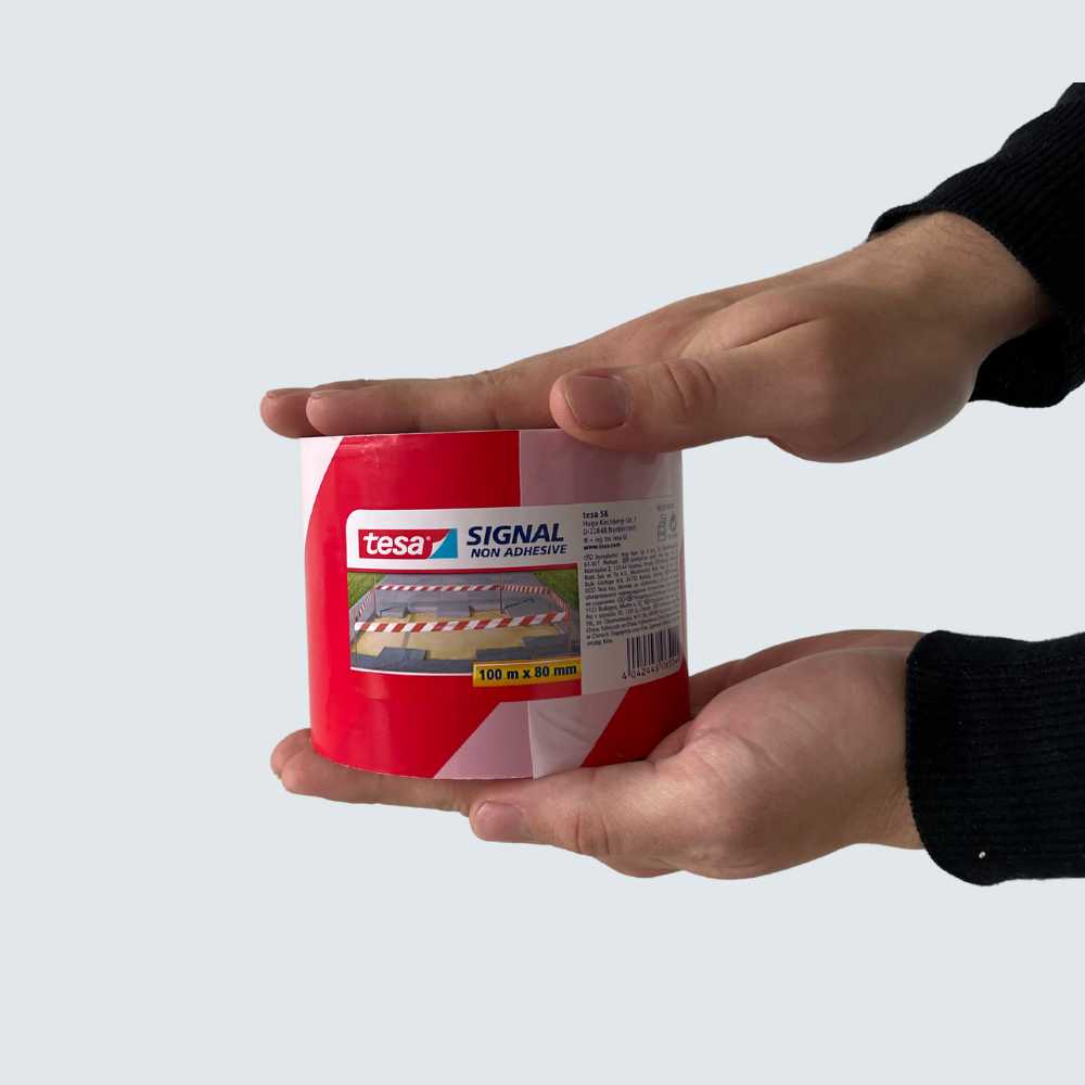 Tesa-Absperrband extra breit liegt zwischen zwei Händen